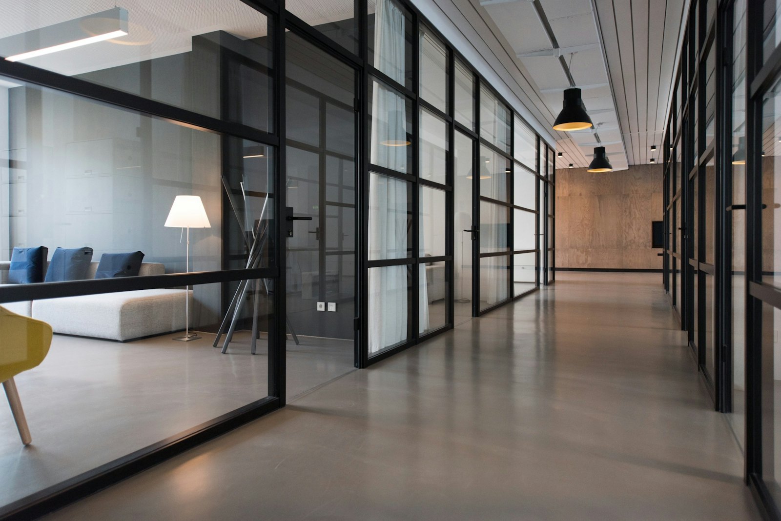 A clean, glass-partitioned office corridor with polished floors